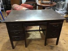 A 1930s oak twin pedestal kneehole desk, the rectangular top above central frieze drawer, flanked by