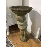 A two part garden bird bath, the circular top with moulded edge and body, supported by a putti (h.