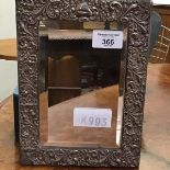 A silver framed mirror, the ornate embossed border enclosing a bevelled plate, with velvet back,