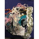 A bag containing a mixed lot of bead necklaces including glass, mother of pearl, polished stone,