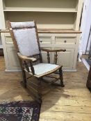 A Victorian elm rocking chair, with upholstered back and seat, with shaped arms, on turned