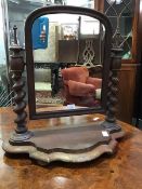 A Victorian mahogany swing mirror, the arched plate supported on barley twist columns, on shaped