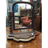 A Victorian mahogany swing mirror, the arched plate supported on barley twist columns, on shaped