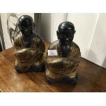 A pair of ebonised and gold painted resin figures of Buddhist monks