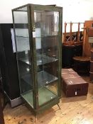 A 1950's freestanding display cabinet, the wooden frame with simulated verdigris finish and cast