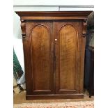 A Victorian plum pudding mahogany wardrobe, the projecting cornice above a pair of moulded trusses