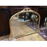 A giltwood overmantel mirror in the 19thc taste, the arched mirror plate within a moulded frame,