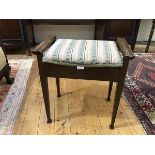 An Edwardian stained beech piano stool, the upholstered hinged seat with tapestry cover within