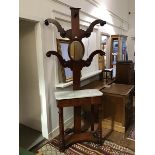 A Victorian mahogany hallstand, the raised back with four branches, with hat pegs and a central oval