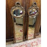 A pair of modern gilt composition wall mirrors in the French taste, the elongated frames embellished