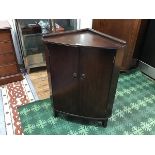 A 1960s corner cabinet by Strongbow Furniture, the top with shallow gallery above a pair of doors,