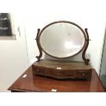 An Edwardian mahogany toilet mirror, the oval bevelled plate within scroll uprights, the