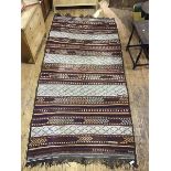 A kelim carpet, the field made up of horizontal bands of madder and ivory with highlights of