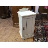 A white painted pot cupboard, with gallery back and moulded top above a panelled door, raised on