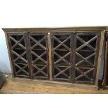 A hardwood bookcase, the projecting top above two pairs of lattice moulded astragal glazed doors,