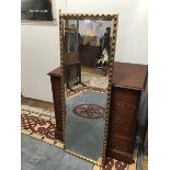 A modern gilt framed wall mirror, the rectangular bevelled plate within a frame decorated with