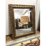 A modern gilt framed wall mirror, the rectangular bevelled plate within a pierced cushion frame,