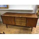 A late 1950s teak sideboard, the rectangular top above a bank of four drawers, flanked by a pair