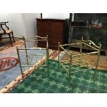A pair of modern brass luggage racks, each with rectangular frame incorporating an arched back and