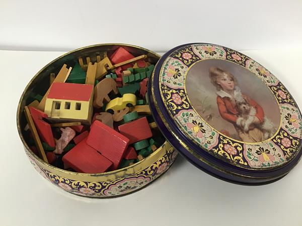 A tin with a collection of treen decorated farmyard animals, farm buildings, fences etc.