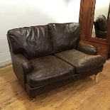 A leather two seater sofa in the Howard style with detachable back and seat cushions and piped