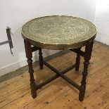 A Middle Eastern brass table top decorated with intricate radiating designs, and Islamic text over a