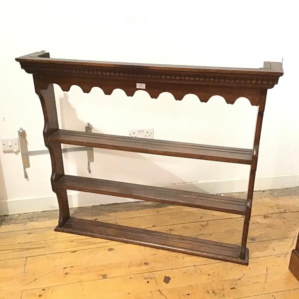 An oak plate rack, the dentil cornice above a shaped frieze with three channel moulded shelves below