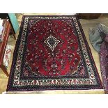 A North West Persian hand knotted wool carpet, the red field with lozenge central medallion outlined