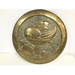 An Arts & Crafts brass circular embossed wall plaque with vase of fruit (d.49cm)