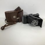 An Ensign camera with bellows lens and leather carry case with shoulder strap