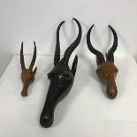 An ebonised carved wood African antelope head, with painted decoration and two similar carved wood