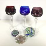 Three Bohemian style ruby, amethyst and blue slice cut hock glasses and three various paperweights