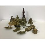 A collection of brass ornaments including a school style bell, a lady bell, a lion desk