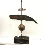 An American folk art style weather vane with whale and ball design and centre column on pine base (