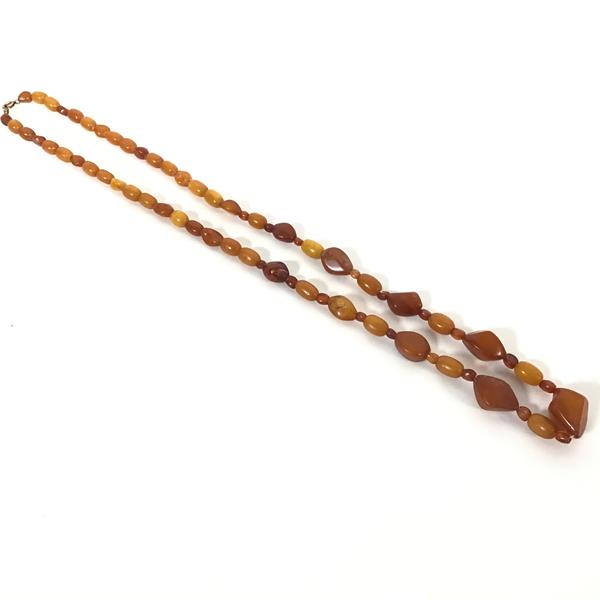 A natural yolk and dark honey coloured amber bead necklace (38cm. largest bead: 2cm) (45.34g)