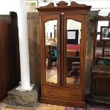 A late Victorian walnut single wardrobe, the shaped cornice above a pair of mirror doors,