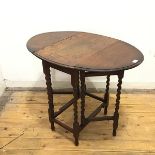A 1920s oak gateleg table, the oval top with moulded edge on spiral turned legs united by straight