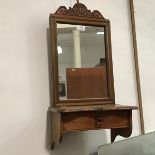 A hanging mirror, the carved cornice above a rectangular plate, with hinged lid below (63cm x 28cm x