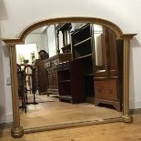 A modern gilt painted overmantle mirror, the arched frame with turned pilasters enclosing a shaped