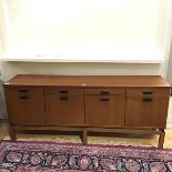 A 1980s teak side cabinet, the rectangular top above four frieze drawers, with four cupboards below,