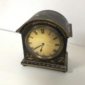 A 1920s lacquered mantel clock with chinoiserie decoration, with arched top over a metal dial with