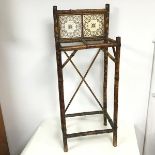 An early 20thc bamboo stick stand with gallery back inset with ceramic tiles, with an X stretcher to