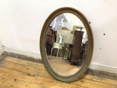 An Edwardian giltwood wall mirror, the oval plate within a fluted and beaded frame (82cm x 58cm)