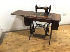 An oak framed Singer treddle sewing machine, the painted iron mechanism highlighted with gilt