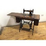 An oak framed Singer treddle sewing machine, the painted iron mechanism highlighted with gilt