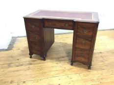 An Edwardian mahogany kneehole desk, the inverted breakfront top with crossbanded border and vinyl