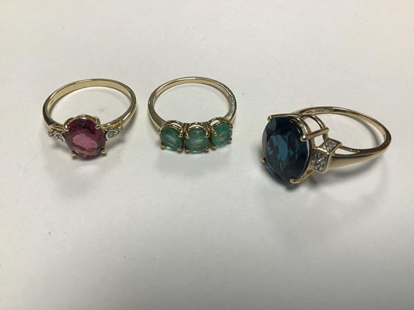 A collection of three 10ct gold rings, one set three emeralds in claw setting, one gem set in claw