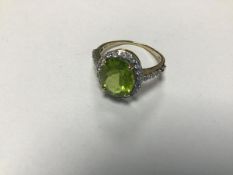 A 9ct gold peridot ring with paste set border and shoulders (one stone missing) (L)