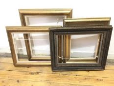 A set of four moulded and gilt picture frames, one with floral carving and another lacquered and