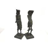 A pair of spelter Continental figure candlesticks, one modelled as a one legged man, the other, a